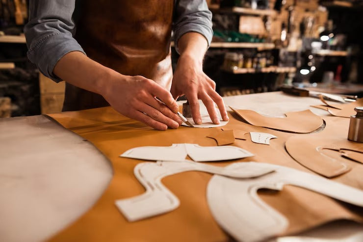 Person working with leather pieces on a table in a workshop setting - Westo Leather
